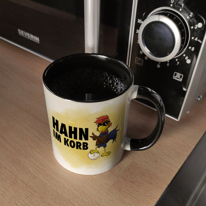 Hahn im Korb Kaffeebecher Schwarz Das einzigartige Cartoon-Motiv eines Hahns macht diesen Kaffeebecher zu einem echt ausgefallenem Geschenk für Kollegen, Familie und Freunde die vielleicht alleine als Hahn im Korb sitzen. mit Cartoon-Hahn, Aufschrift Moti