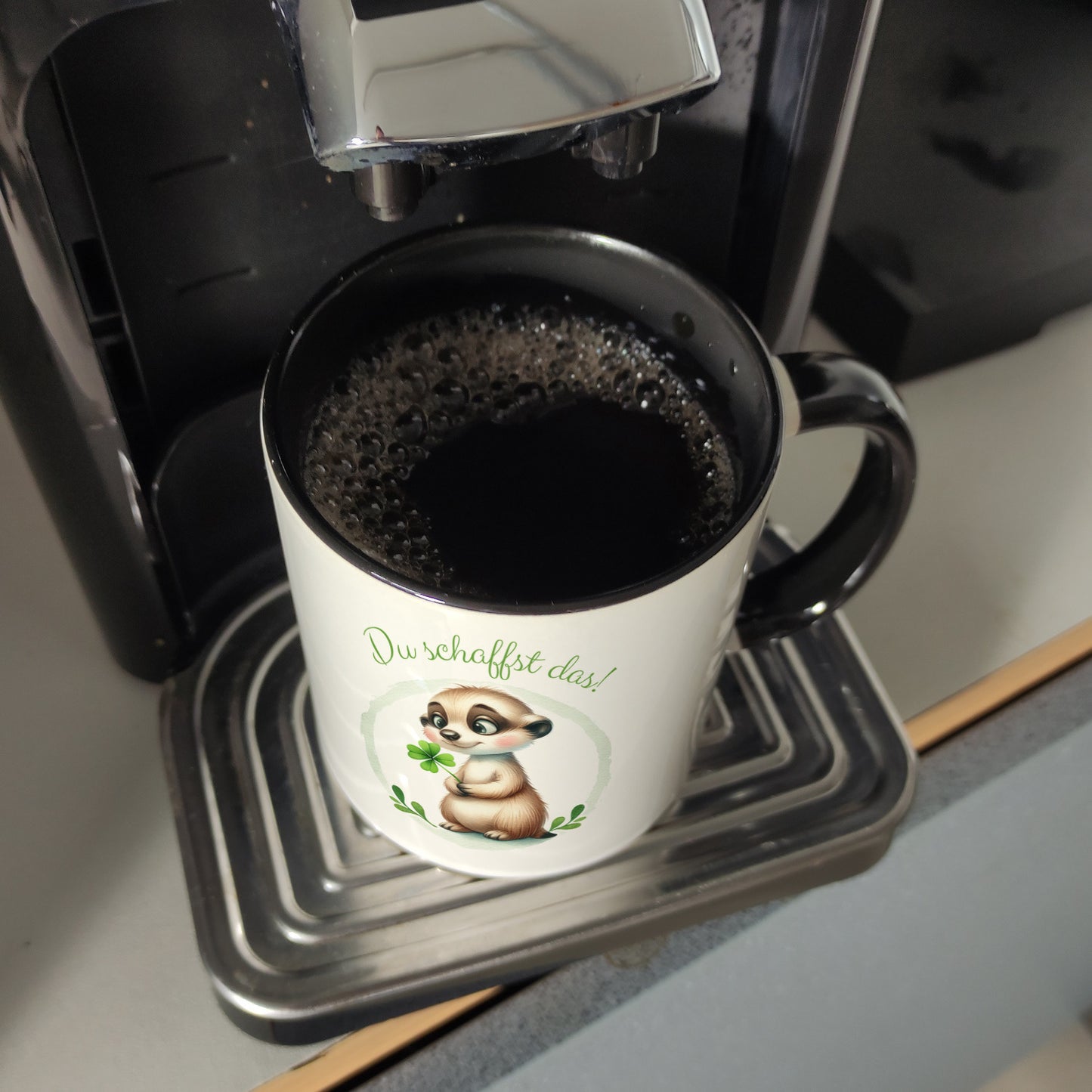 Erdmännchen mit Kleeblatt Kaffeebecher in schwarz mit Spruch Du schaffst das