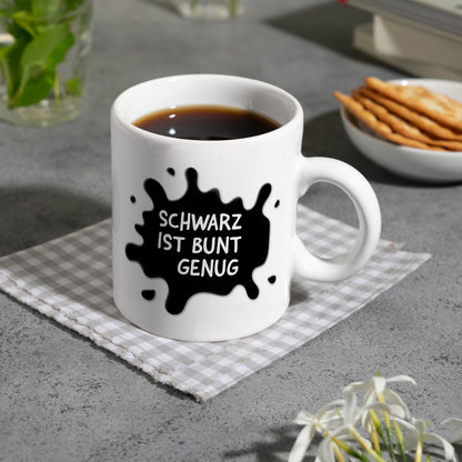 Schwarz ist bunt genug Kaffeebecher mit Farbklecks Motiv